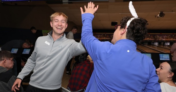 UNK junior Dylan Pfeifer celebrates with a Buddy Bowling participant during last week’s event at Big Apple Fun Center in Kearney. (Photo by Erika Pritchard, UNK Communications)